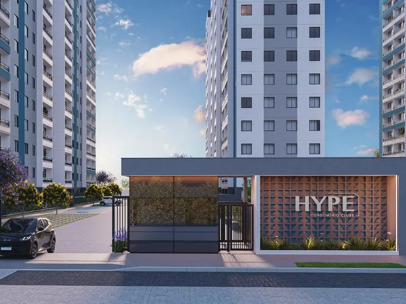 Portaria do Hype Condomínio Clube, com o letreiro em cobogó iluminado e as torres ao fundo